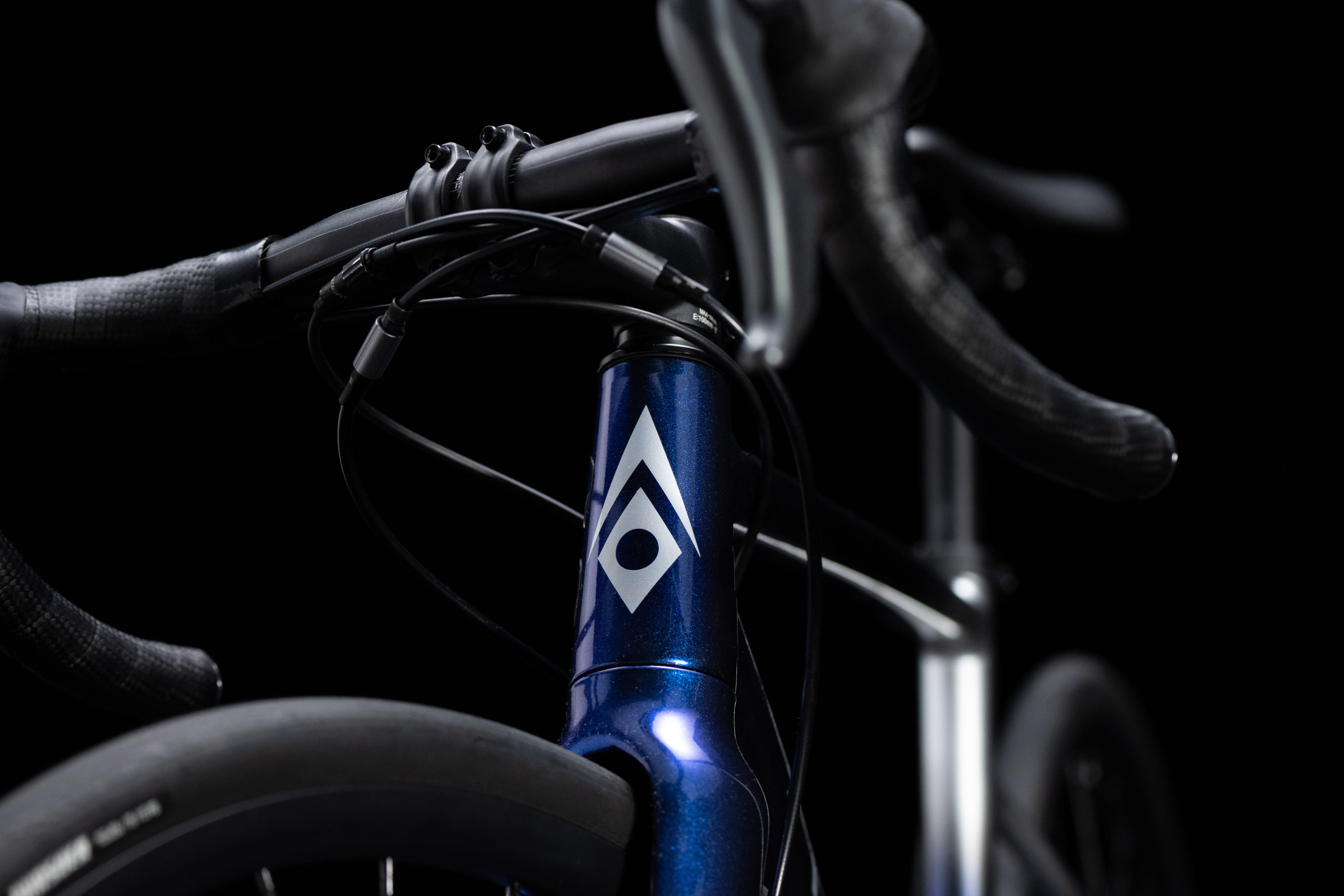 ロードバイクのハンドルとフレーム、深い青色のフレームにユニークなロゴがデザインされているクローズアップショット